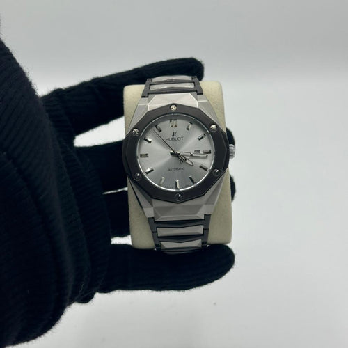 Hublot watch held by a gloved hand on a light gray background